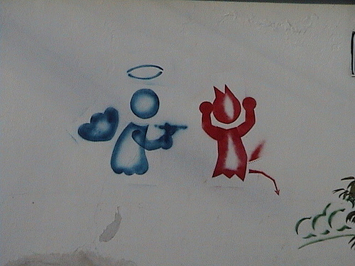 Pintada callejera representando a un ángel amenazando a un demonio