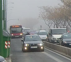 Tráfico en una avenida bajo la niebla de una mañana en Sevilla