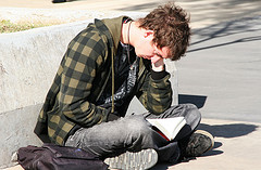 Chico sentado en la calle concentrado en un libro