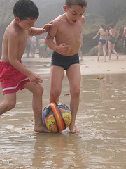 Dos niños jugando a fútbol en la playa