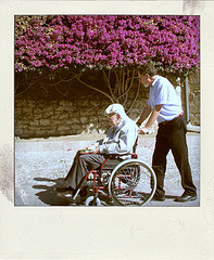 Hombre paseando a otro mayor en silla de ruedas