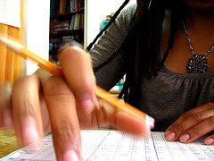 primer plano de la mano de una chica con un lápiz haciendo cálculos.