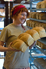 Chica con varias hogazas de pan en las manos